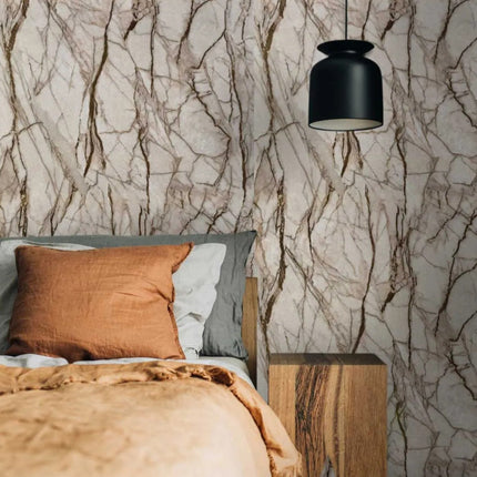 Bedroom with marble-patterned wall panels, bed with pillows, and wooden nightstand.