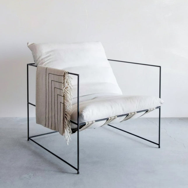 Modern chair with a black frame and white cushion on a light gray floor.