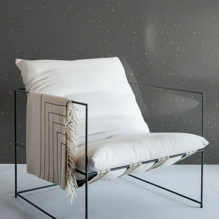 Modern chair with white cushion and beige blanket against a gray background